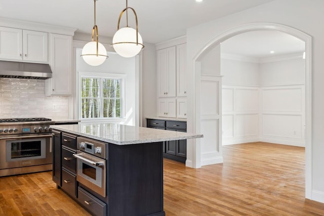 131 Exeter Rd, North Hampton, NH 03862 - kitchen with appliances with stainless steel finishes, arched walkways, a decorative wall, white cabinets, and under cabinet range hood