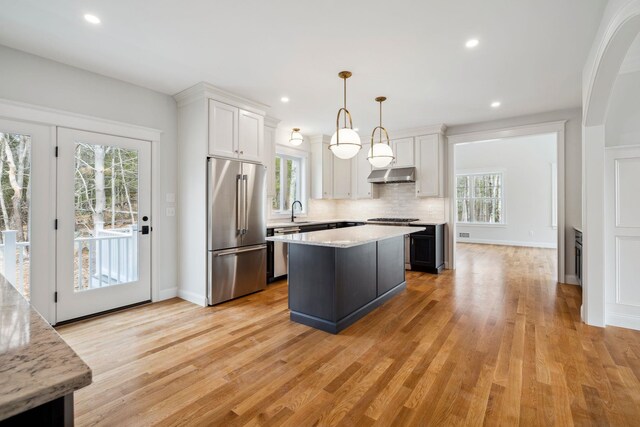 131 Exeter Rd, North Hampton, NH 03862 - kitchen with stainless steel appliances, under cabinet range hood, white cabinetry, backsplash, and light wood-style floors