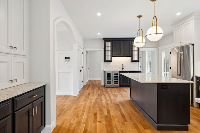 131 Exeter Rd, North Hampton, NH 03862 - kitchen featuring beverage cooler, glass insert cabinets, recessed lighting, light wood-style floors, and backsplash