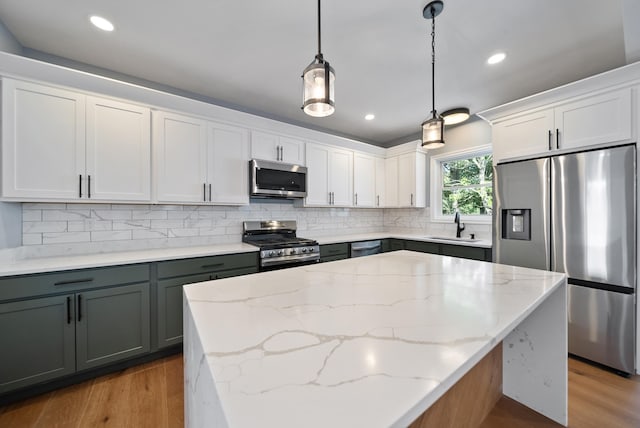 13 Raven St, Nashua, NH 03060 - kitchen with appliances with stainless steel finishes, wood finished floors, decorative backsplash, hanging light fixtures, and recessed lighting
