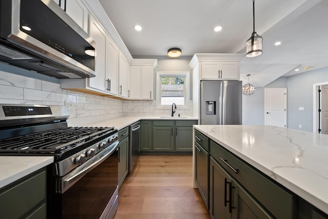 13 Raven St, Nashua, NH 03060 - kitchen with stainless steel appliances, green cabinetry, decorative backsplash, white cabinetry, and light wood-type flooring
