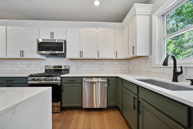 13 Raven St, Nashua, NH 03060 - kitchen featuring stainless steel appliances, green cabinetry, white cabinetry, light wood finished floors, and decorative backsplash