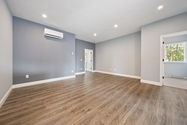 13 Raven St, Nashua, NH 03060 - empty room featuring a wall unit AC, recessed lighting, wood finished floors, and a baseboard radiator