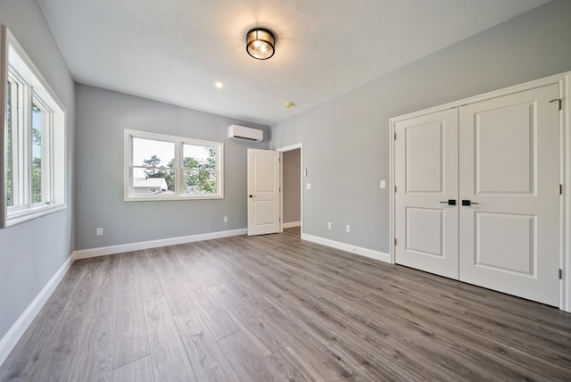 13 Raven St, Nashua, NH 03060 - unfurnished bedroom featuring a wall unit AC, wood finished floors, and a closet