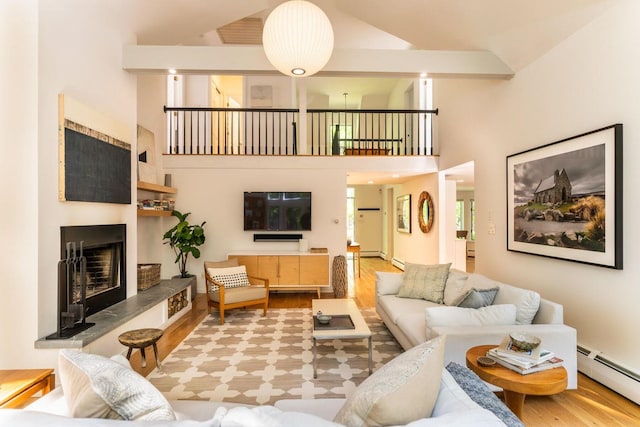 137 Wildes District Rd, Kennebunkport, ME 04046 - living area featuring wood finished floors, a baseboard heating unit, high vaulted ceiling, a fireplace with raised hearth, and baseboard heating