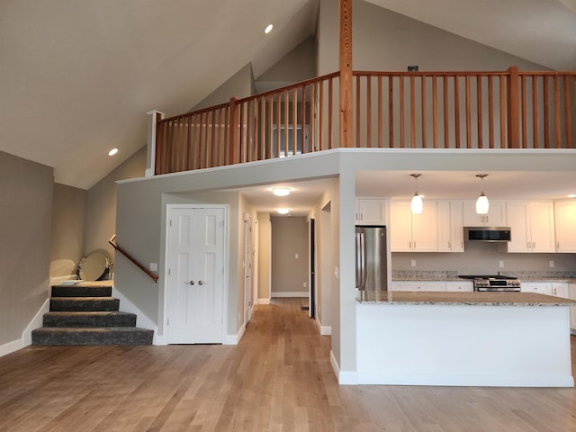 22 John Hardie Way, Chichester, NH 03234 - kitchen with stainless steel appliances, white cabinets, high vaulted ceiling, light stone countertops, and light wood-style flooring