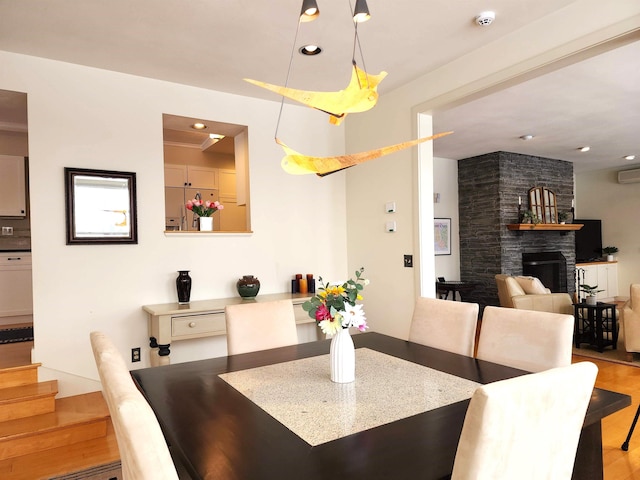 201 Lower Judson Ln, Stowe, VT 05672 - dining room featuring a stone fireplace, wood finished floors, stairs, recessed lighting, and a wall mounted air conditioner