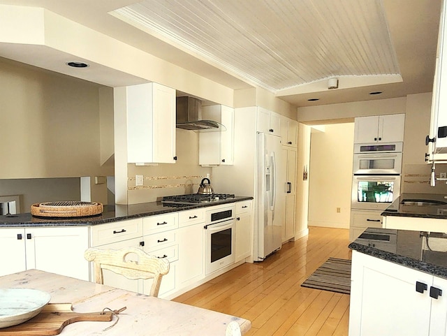 201 Lower Judson Ln, Stowe, VT 05672 - kitchen featuring appliances with stainless steel finishes, white cabinets, wall chimney exhaust hood, light wood finished floors, and dark stone countertops