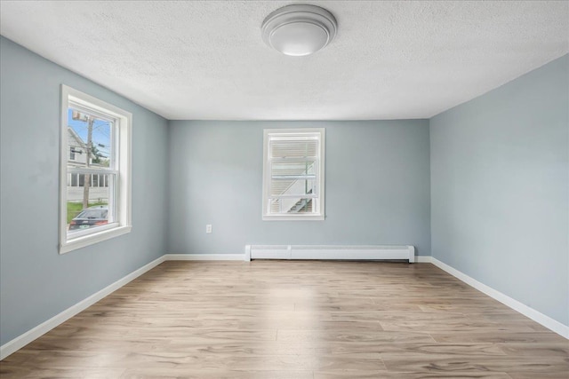 10 Lafountain St, Winooski, VT 05404 - empty room with baseboard heating, wood finished floors, and a textured ceiling