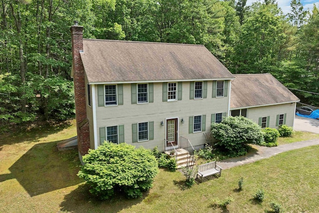 4 June Bug Ln, Wolfeboro, NH 03894 - colonial house with a chimney, a shingled roof, a front yard, and a wooded view