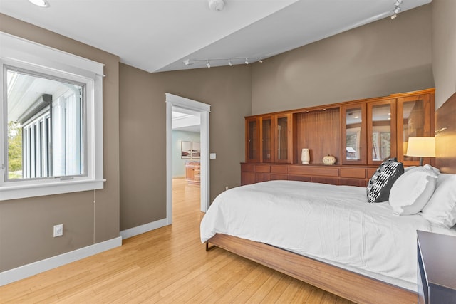 214 Upper Hollow Rd, Stowe, VT 05672 - bedroom with rail lighting, light wood-style flooring, and vaulted ceiling