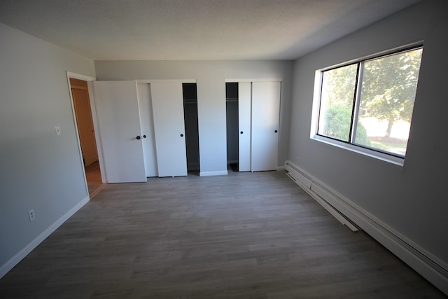 11 Tiffany Rd Unit 5, Salem, NH 03079 - unfurnished bedroom with a baseboard radiator, multiple closets, and wood finished floors