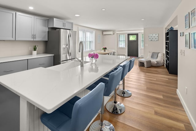 2366 Mountain Rd Unit 1, Stowe, VT 05672 - kitchen featuring stainless steel fridge, a kitchen breakfast bar, light wood-type flooring, a wall unit AC, and recessed lighting