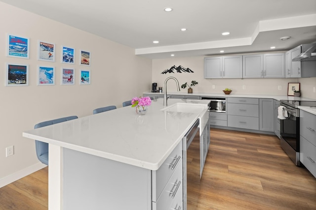 2366 Mountain Rd Unit 1, Stowe, VT 05672 - kitchen featuring appliances with stainless steel finishes, gray cabinets, recessed lighting, a breakfast bar area, and a center island with sink