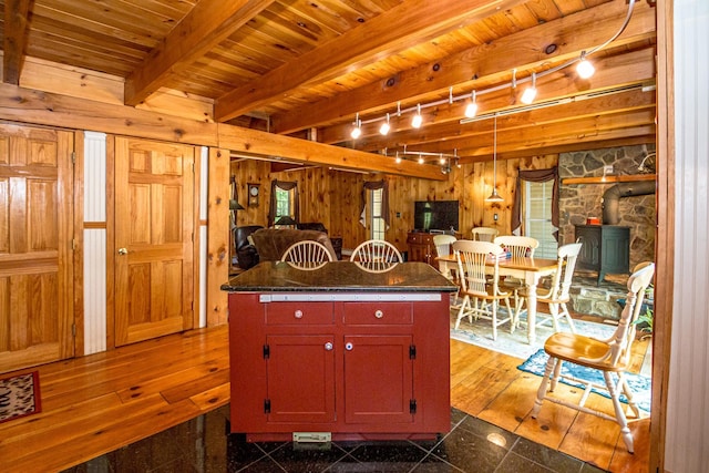 20 Pine Lane Rd, Ossipee, NH 03890 - kitchen featuring a wood stove, dark countertops, wood walls, a wooden ceiling with exposed beams, and granite floors