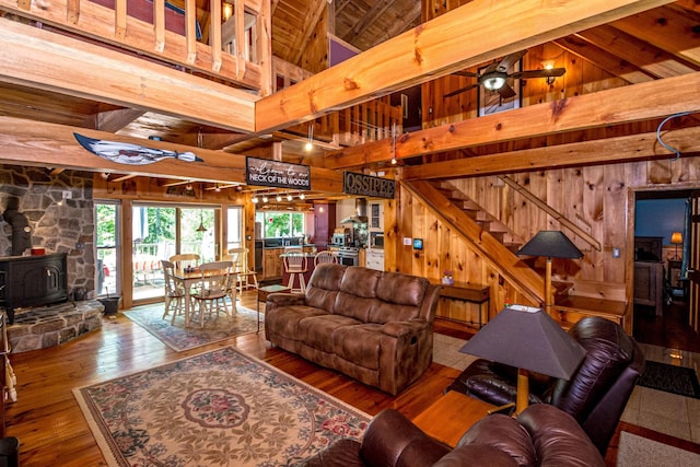 20 Pine Lane Rd, Ossipee, NH 03890 - living room with wooden walls, a wood stove, hardwood / wood-style flooring, stairs, and high vaulted ceiling