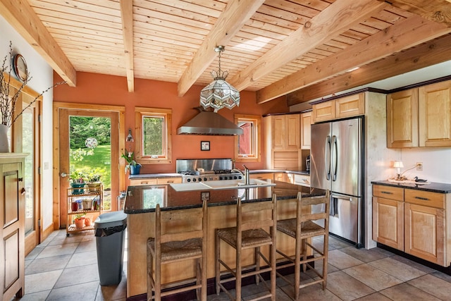 532 Randolph Rd, Stowe, VT 05672 - kitchen with freestanding refrigerator, light brown cabinets, range, wall chimney range hood, and an island with sink