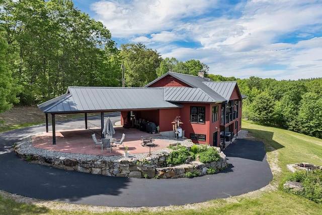 3 Simon Hill Rd, Ossipee, NH 03864 - view of front of house with a carport, a chimney, a metal roof, a standing seam roof, and a patio area