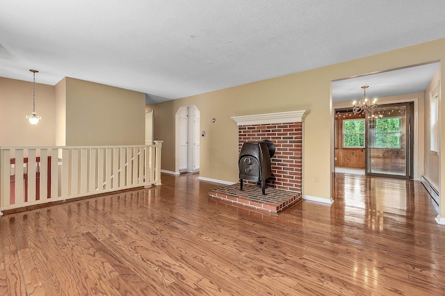 2 Littlehale Rd, Durham, NH 03824 - unfurnished living room with wood finished floors, a baseboard heating unit, a wood stove, and a chandelier
