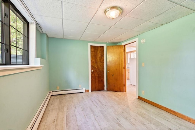 23 Riverlake St, Alton, NH 03810 - empty room with a baseboard heating unit, wood finished floors, a drop ceiling, and a baseboard radiator
