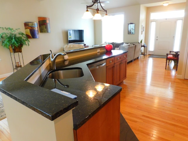 150 Pleasant Pond Way Unit 15, Manchester, NH 03102 - kitchen featuring stainless steel dishwasher, light wood-style flooring, open floor plan, a kitchen island with sink, and brown cabinets