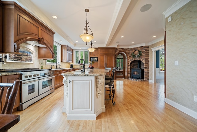 3 Baldwin Ln, Bedford, NH 03110 - kitchen with double oven range, light stone counters, an island with sink, brown cabinets, and light wood-style flooring