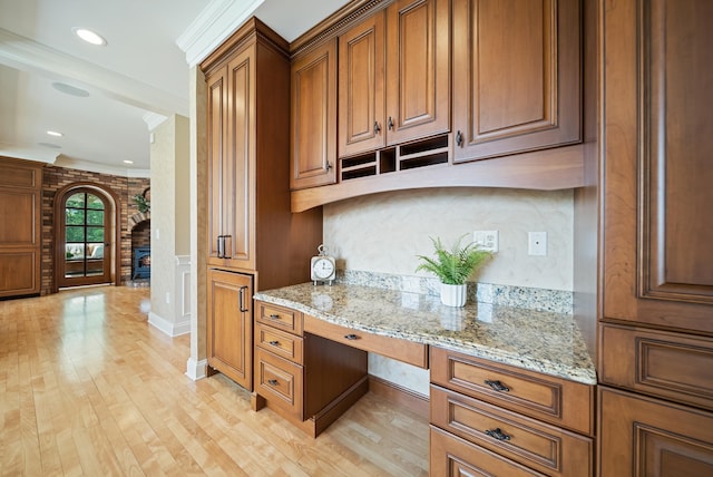 3 Baldwin Ln, Bedford, NH 03110 - kitchen with crown molding, light wood-style flooring, brown cabinetry, light stone countertops, and built in study area