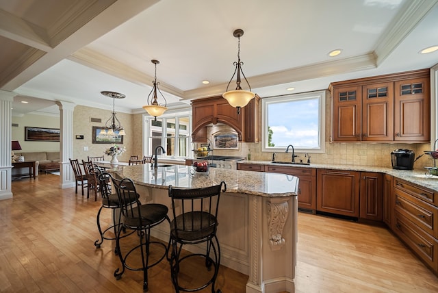 3 Baldwin Ln, Bedford, NH 03110 - kitchen with ornate columns, light wood-style floors, light stone counters, a kitchen breakfast bar, and crown molding