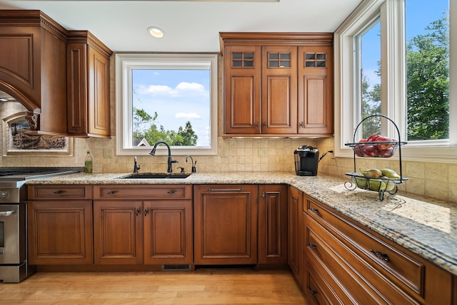 3 Baldwin Ln, Bedford, NH 03110 - kitchen with stainless steel range with gas stovetop, tasteful backsplash, light stone countertops, brown cabinets, and plenty of natural light