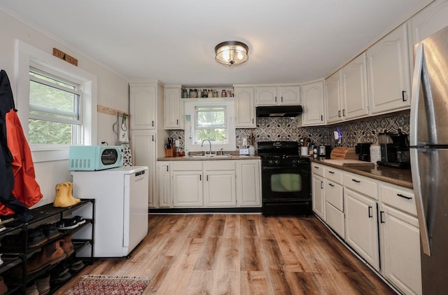 5 School St, Tilton, NH 03276 - kitchen featuring black gas range oven, under cabinet range hood, freestanding refrigerator, white microwave, and backsplash