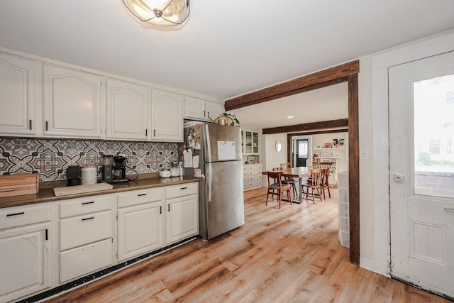 5 School St, Tilton, NH 03276 - kitchen featuring freestanding refrigerator, white cabinets, tasteful backsplash, light wood finished floors, and beam ceiling