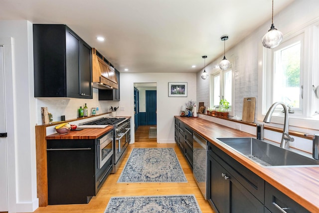 121 Main St, New Ipswich, NH 03071 - kitchen featuring wood counters, dark cabinets, custom range hood, stainless steel appliances, and light wood finished floors