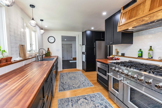 121 Main St, New Ipswich, NH 03071 - kitchen featuring butcher block countertops, appliances with stainless steel finishes, premium range hood, dark cabinets, and backsplash