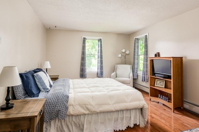 1 Constable Rd, Durham, NH 03824 - bedroom with wood finished floors, multiple windows, a baseboard heating unit, and a textured ceiling