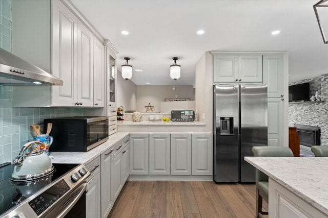 149 Club Sugarbush N Rd, Warren, VT 05674 - kitchen with appliances with stainless steel finishes, wall chimney range hood, decorative backsplash, dark wood-style flooring, and light stone counters