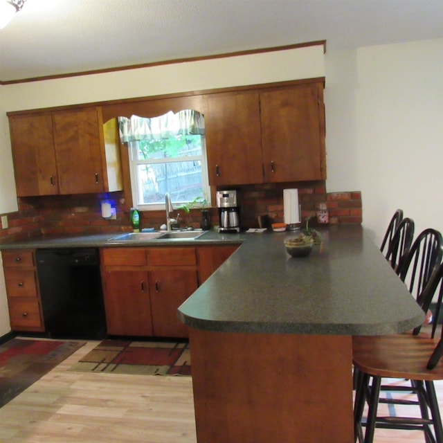 129 Chestnut St, Claremont, NH 03743 - kitchen with black dishwasher, a peninsula, brown cabinets, a kitchen bar, and backsplash