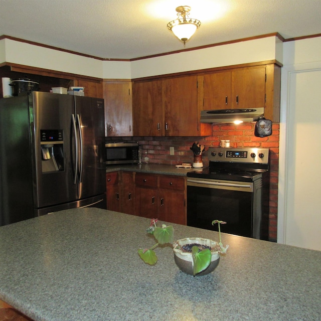 129 Chestnut St, Claremont, NH 03743 - kitchen with appliances with stainless steel finishes, under cabinet range hood, crown molding, tasteful backsplash, and brown cabinetry