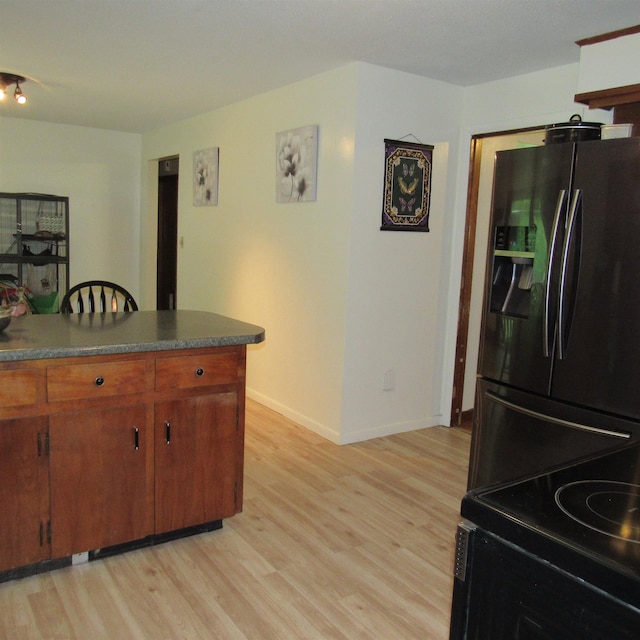 129 Chestnut St, Claremont, NH 03743 - kitchen with fridge with ice dispenser, light wood finished floors, dark countertops, and brown cabinets