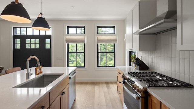 3148 Mountain Rd Unit B, Stowe, VT 05672 - kitchen featuring wall chimney exhaust hood, stainless steel appliances, light wood-style floors, decorative backsplash, and light countertops