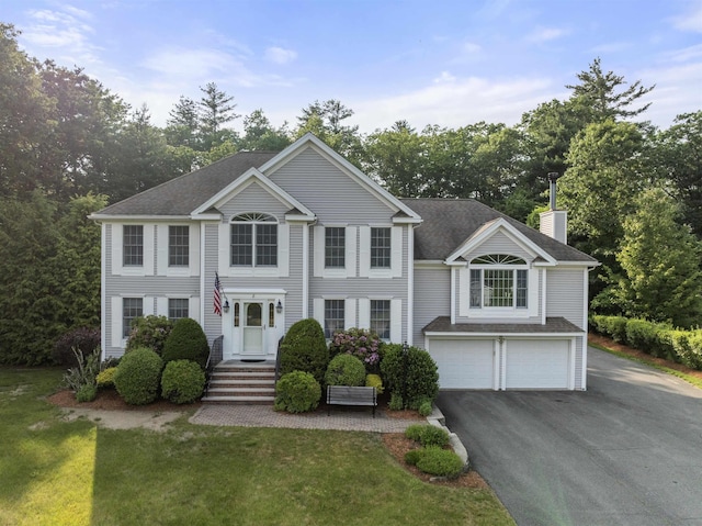 8 Aulson Rd, Salem, NH 03079 - view of front of home featuring an attached garage, a chimney, driveway, a front lawn, and view of wooded area