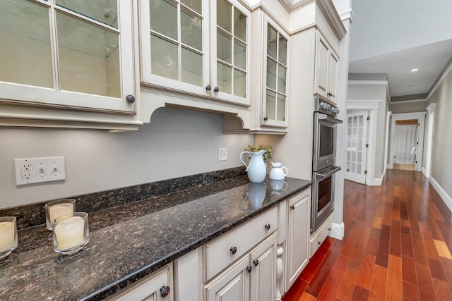 85 Blueberry Hill Rd, Meredith, NH 03253 - kitchen featuring stainless steel double oven, glass insert cabinets, dark wood-type flooring, dark stone counters, and crown molding
