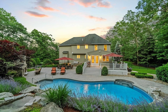 104 Windsor Dr, Auburn, NH 03032 - back of property at dusk featuring a wooden deck, an outdoor pool, outdoor dining area, a patio area, and french doors
