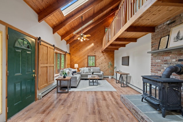 26 Old Mill Rd, Ossipee, NH 03890 - living room with a wood stove, a baseboard radiator, a barn door, a skylight, and a wooden ceiling with exposed beams