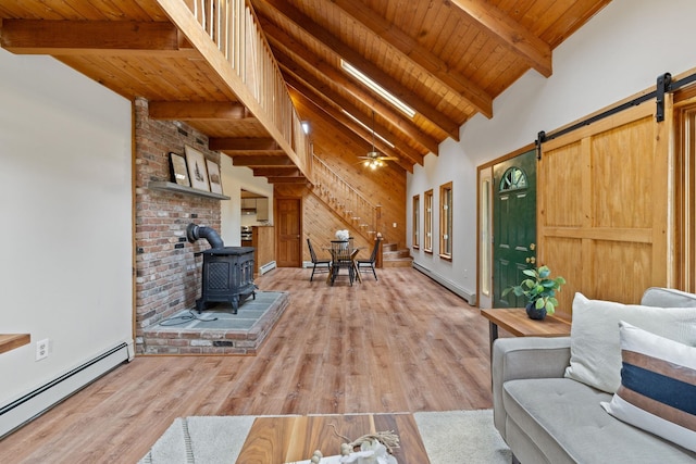 26 Old Mill Rd, Ossipee, NH 03890 - living room with a baseboard radiator, a wood stove, a barn door, stairs, and wood finished floors