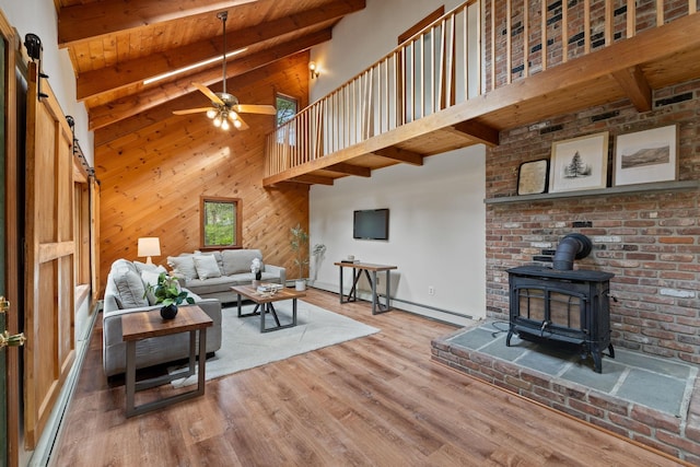 26 Old Mill Rd, Ossipee, NH 03890 - living room featuring beamed ceiling, a wood stove, a baseboard radiator, a ceiling fan, and high vaulted ceiling