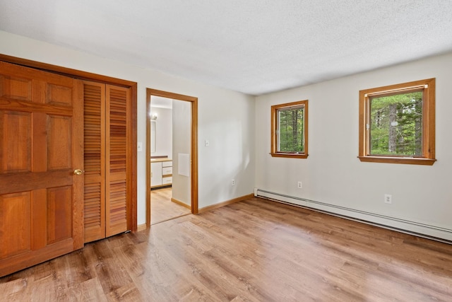 26 Old Mill Rd, Ossipee, NH 03890 - unfurnished bedroom with a baseboard radiator, light wood finished floors, a closet, and a textured ceiling