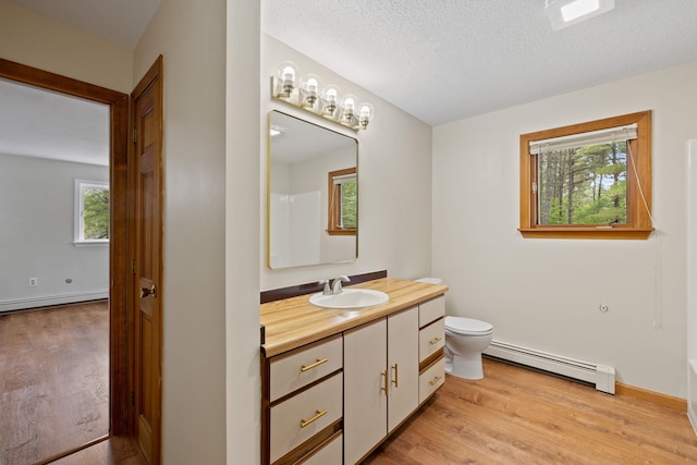 26 Old Mill Rd, Ossipee, NH 03890 - full bath with a baseboard heating unit, wood finished floors, vanity, and a textured ceiling