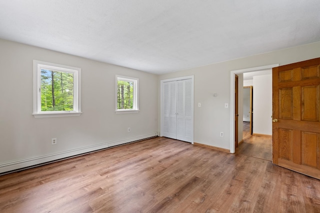 26 Old Mill Rd, Ossipee, NH 03890 - unfurnished bedroom featuring wood finished floors, baseboard heating, and a closet