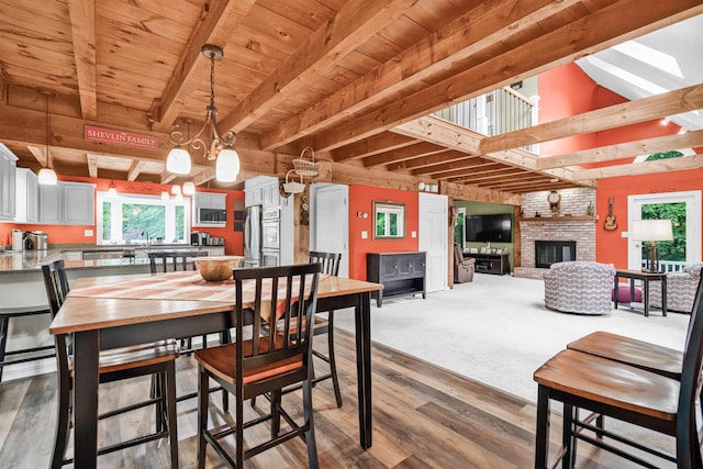 329 Peverly Rd, Northfield, NH 03276 - dining space featuring wood finished floors, a fireplace, a wooden ceiling with exposed beams, and a chandelier