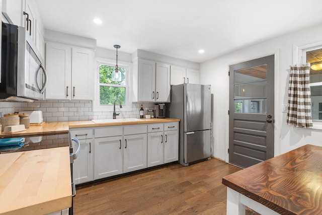 46 E Diane Dr, Keene, NH 03431 - kitchen featuring butcher block counters, stainless steel appliances, decorative backsplash, dark wood-style floors, and hanging light fixtures